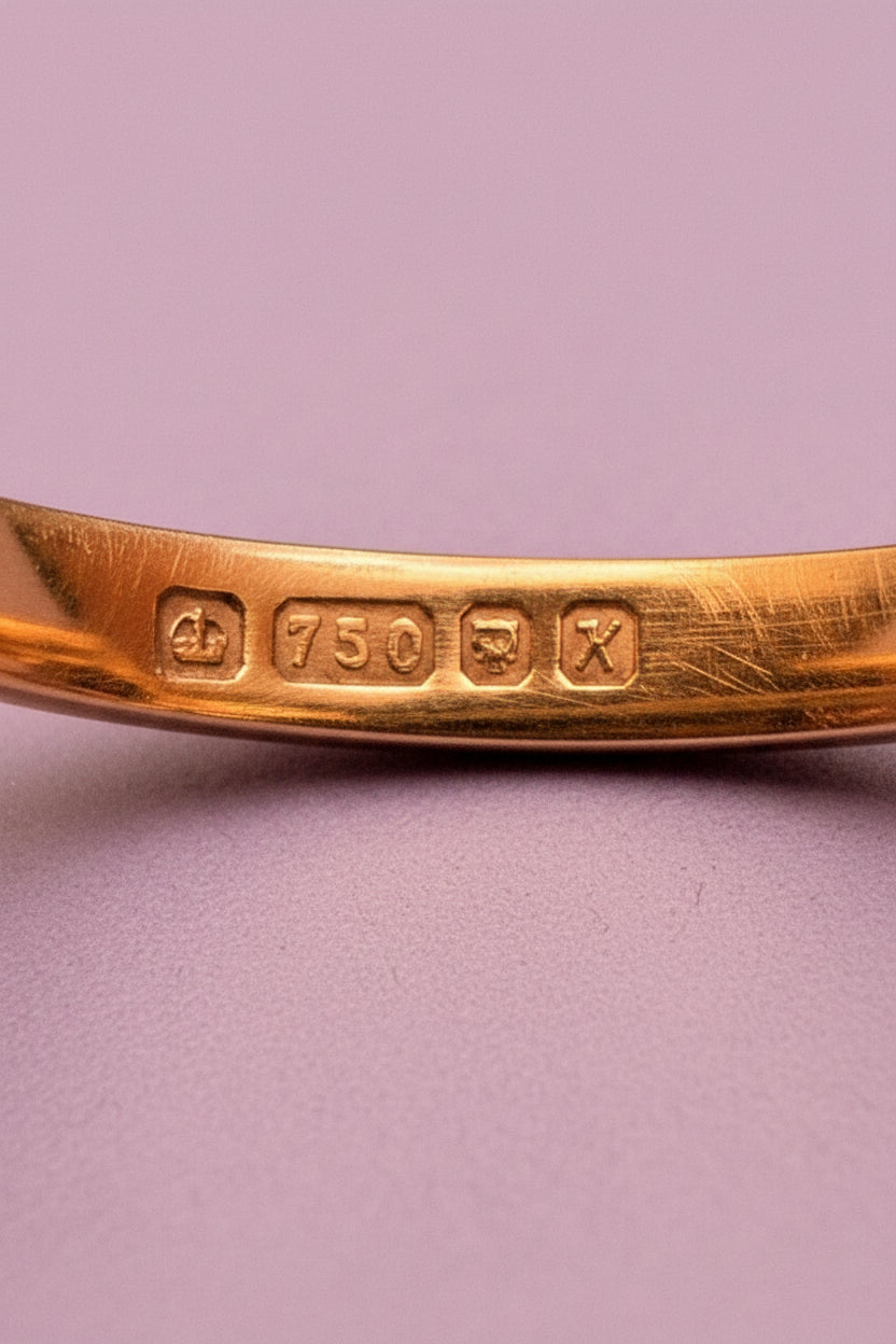 Close of full British Hallmarks showing the Crown (Gold), '750' for 18ct gold, a leopard's head for the London Assay office and a lower case 'k' in an octagonal shape for the year 2005