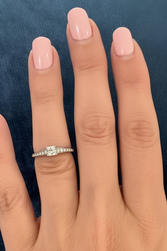 Hand wearing a diamond ring on a blue textured background canadian maple leaf diamond princess cut canadian diamond - ethically sourced from Ekati mine in Canada