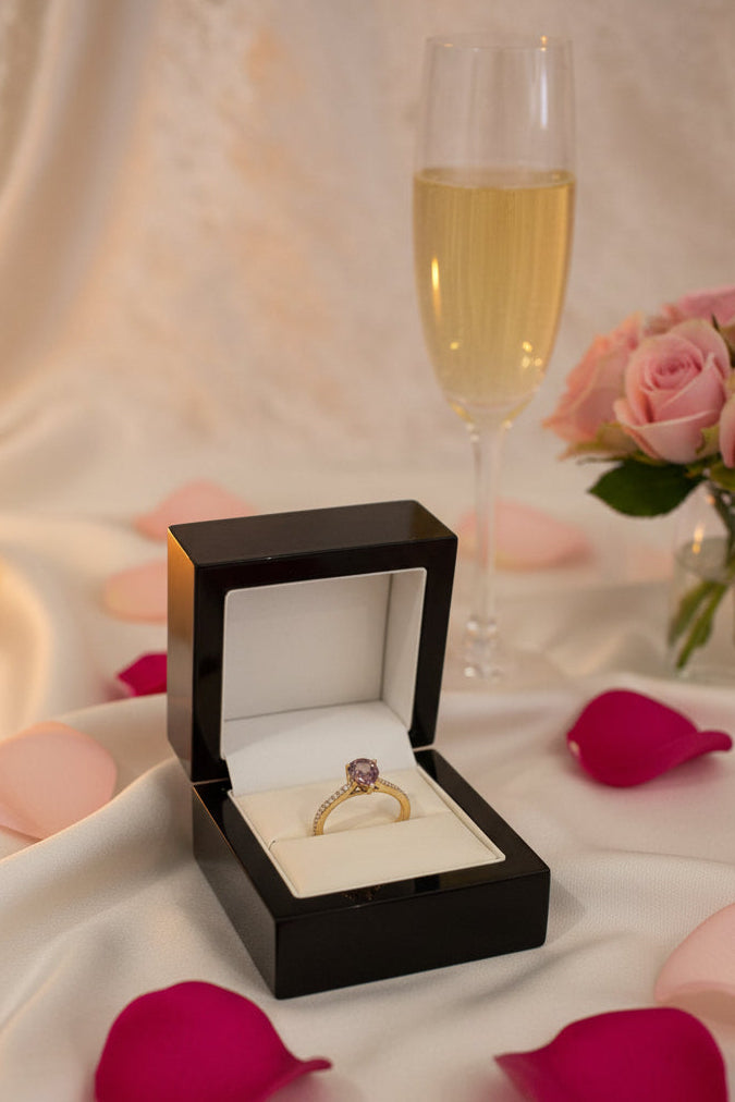 brown sapphire and diamond engagement ring on a table with champagne and flowers