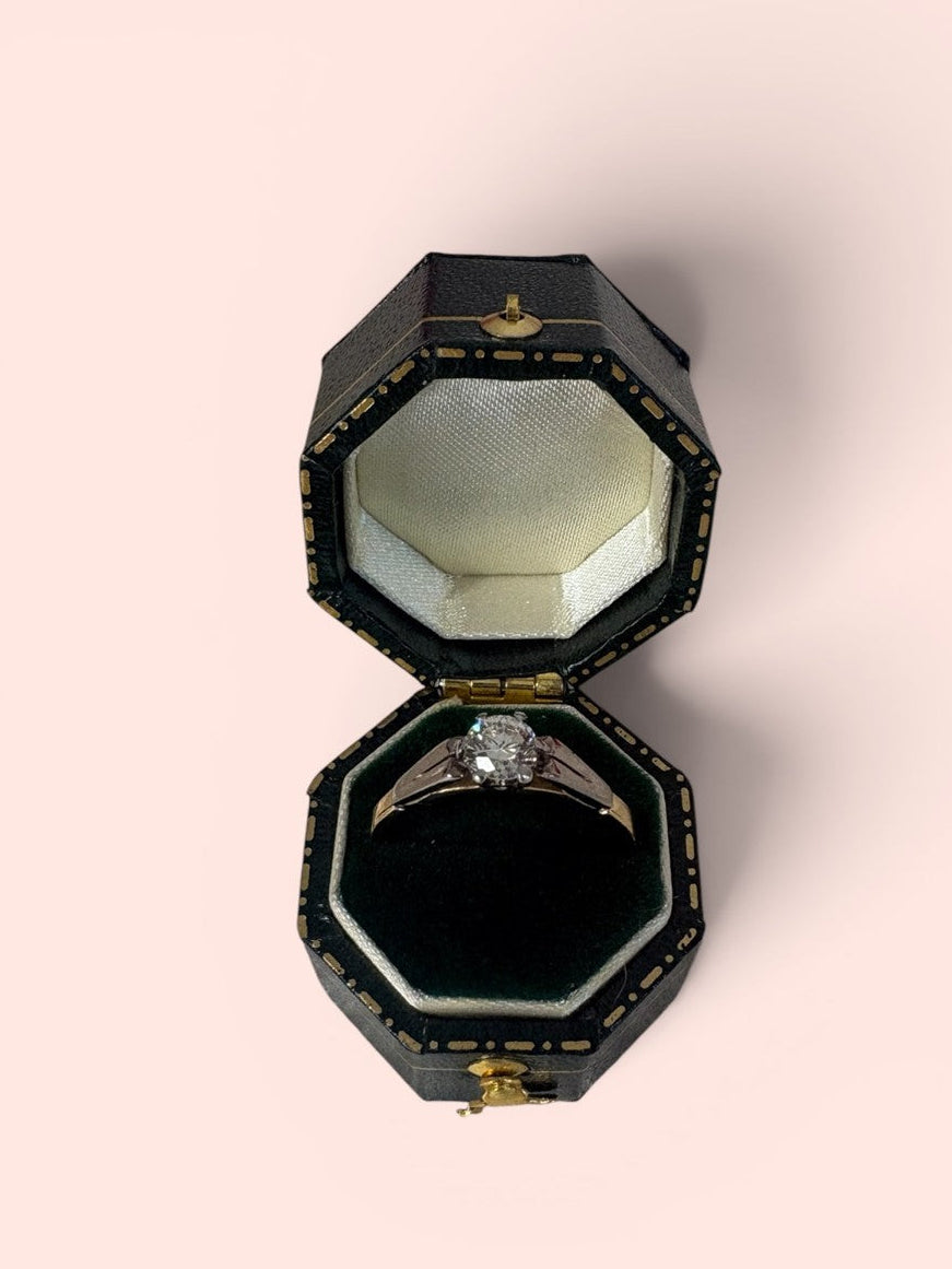 Black jewelry box with a transitional cut diamond solitaire ring inside on a light pink background