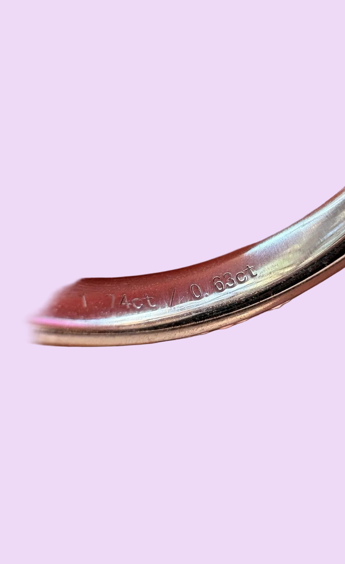 Close-up of the inside of a polished platinum ring, showing engraved metal purity and diamond weight markings.