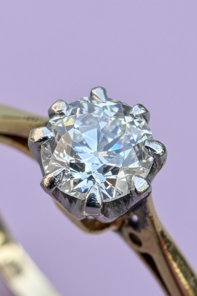 Gold ring with a diamond with chunky facets and open culet on a lilac 
background