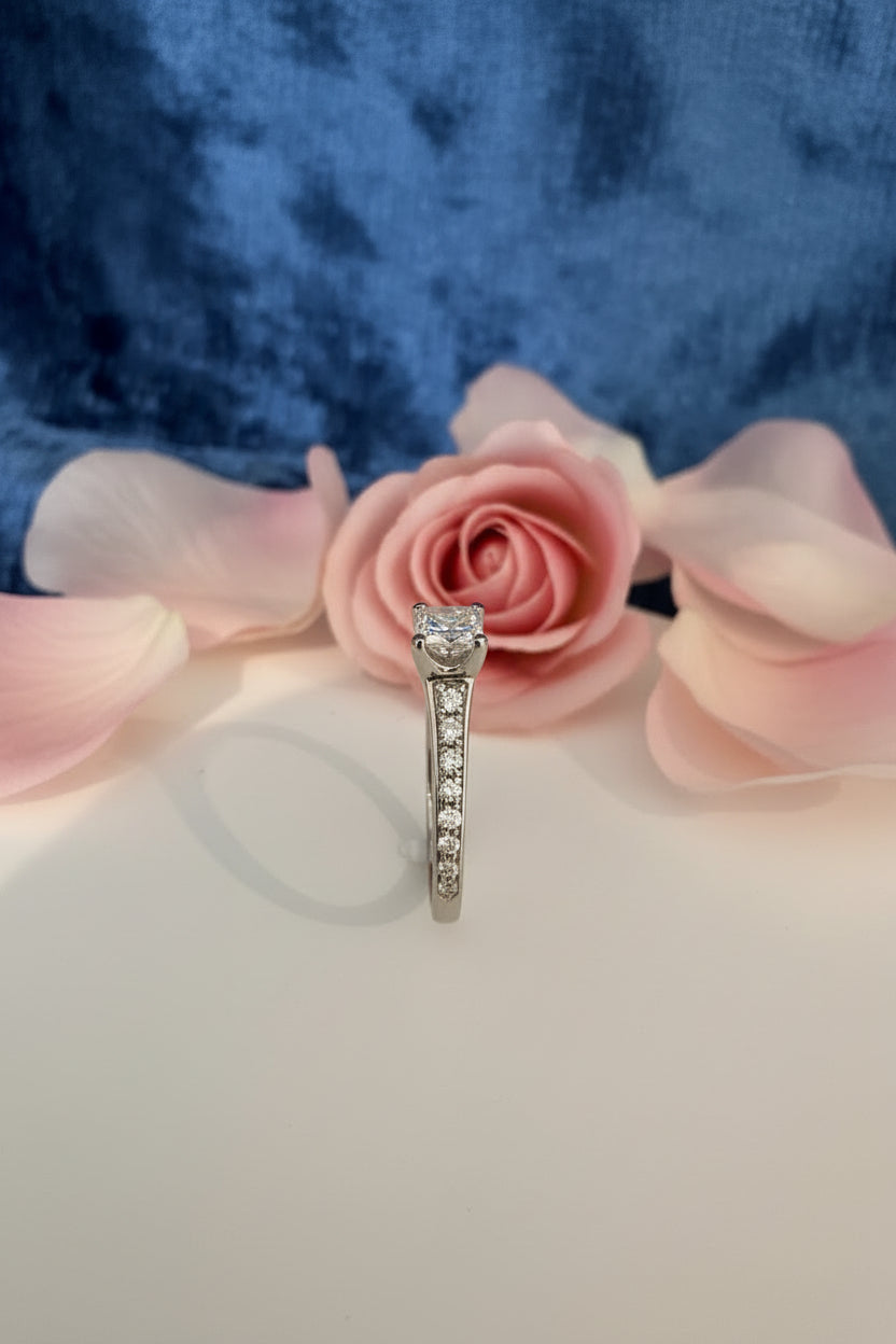 Diamond ring on a white table with pink flowers and blue background