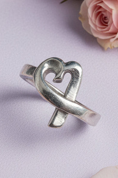 Silver heart ring on a lilac background with roses