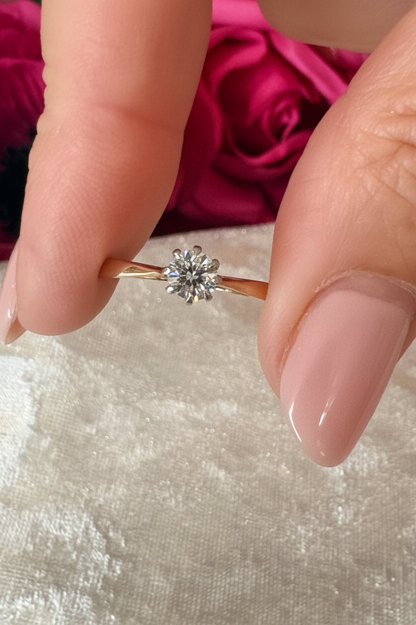 Close-up of a gold ring with a diamond on a textured surface