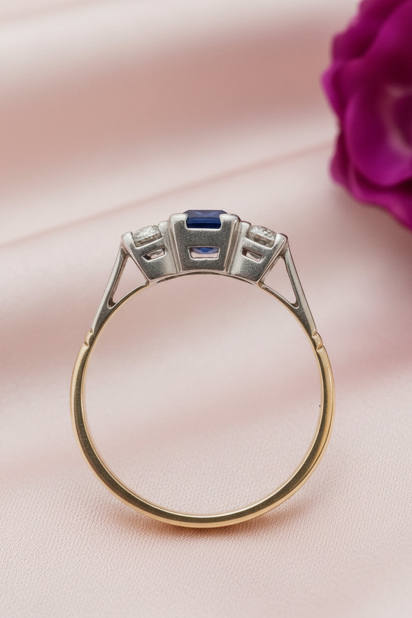 Side on view of a 18ct gold ring with sapphire and two old cut diamonds
