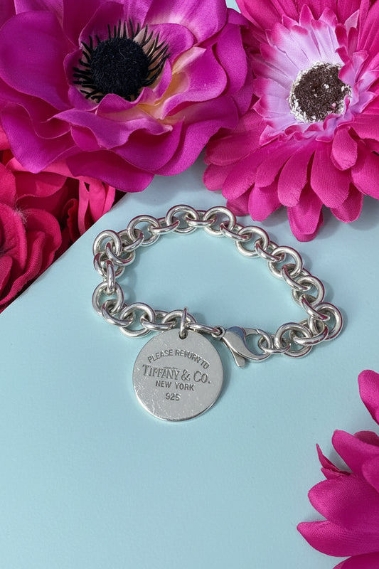 silver tiffany round tag Return to Tiffany bracelet on light blue background with fuscia pink flowers