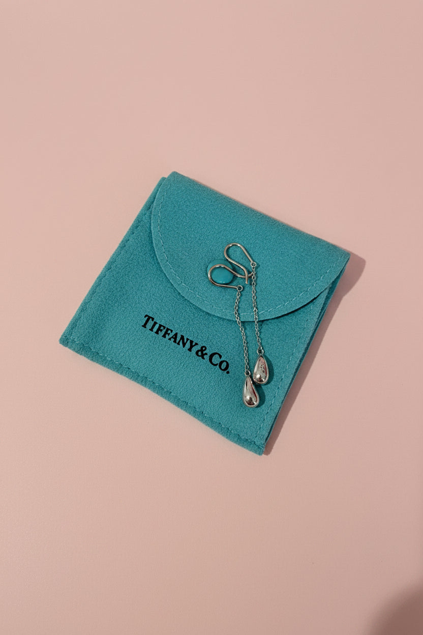 Tiffany & Co. Elsa Peretti Bean earrings on a blue jewelry pouch on a textured surface