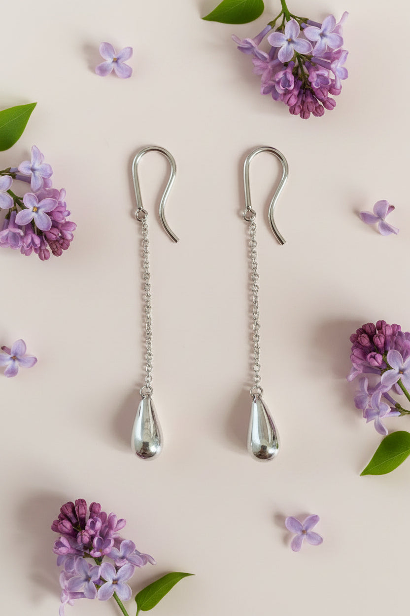 Silver earring clips on a cream background with lilac flowers