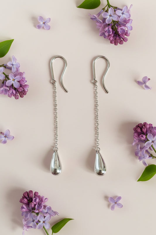 Silver earring clips on a cream background with lilac flowers