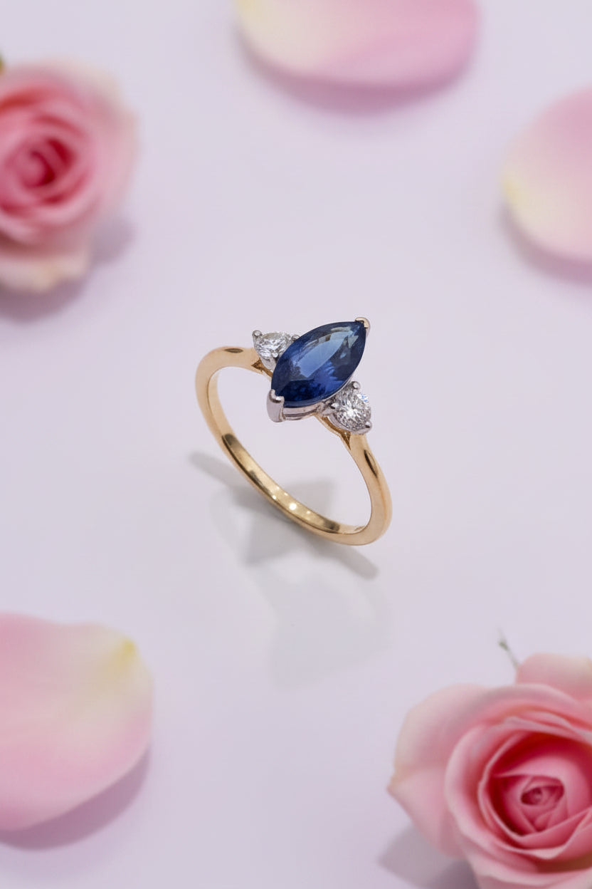 18ct Gold ring with a blue sapphire and two diamonds on a white surface