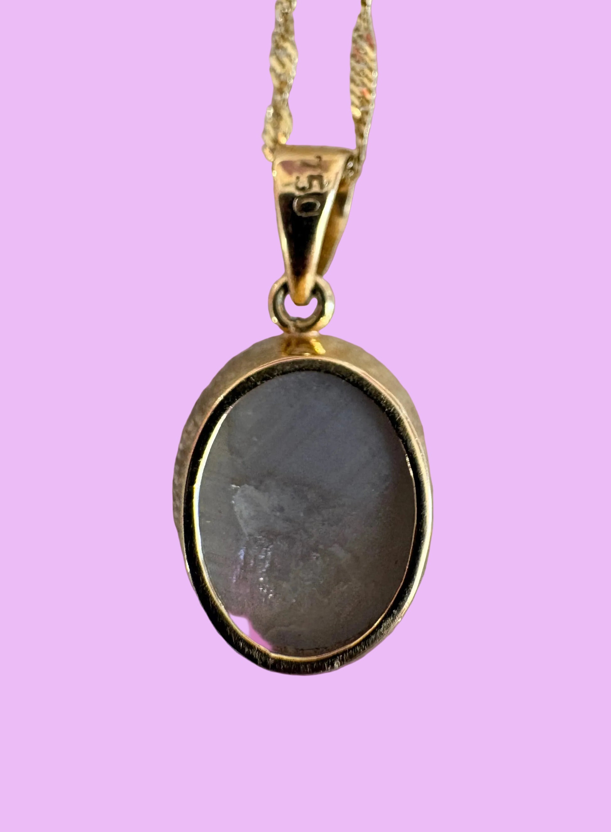 Gold necklace with a pendant on a pink background