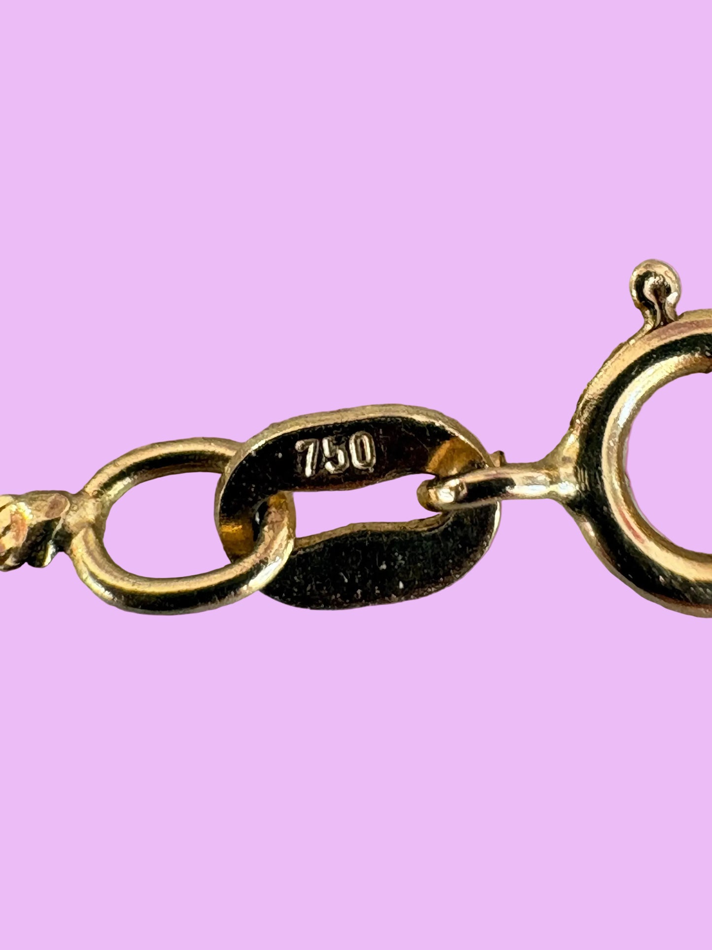 Gold chain with a tag on a pink background