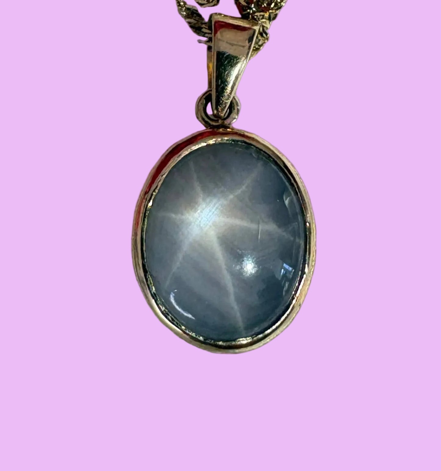 Necklace with a starsapphire pendant on a pink background