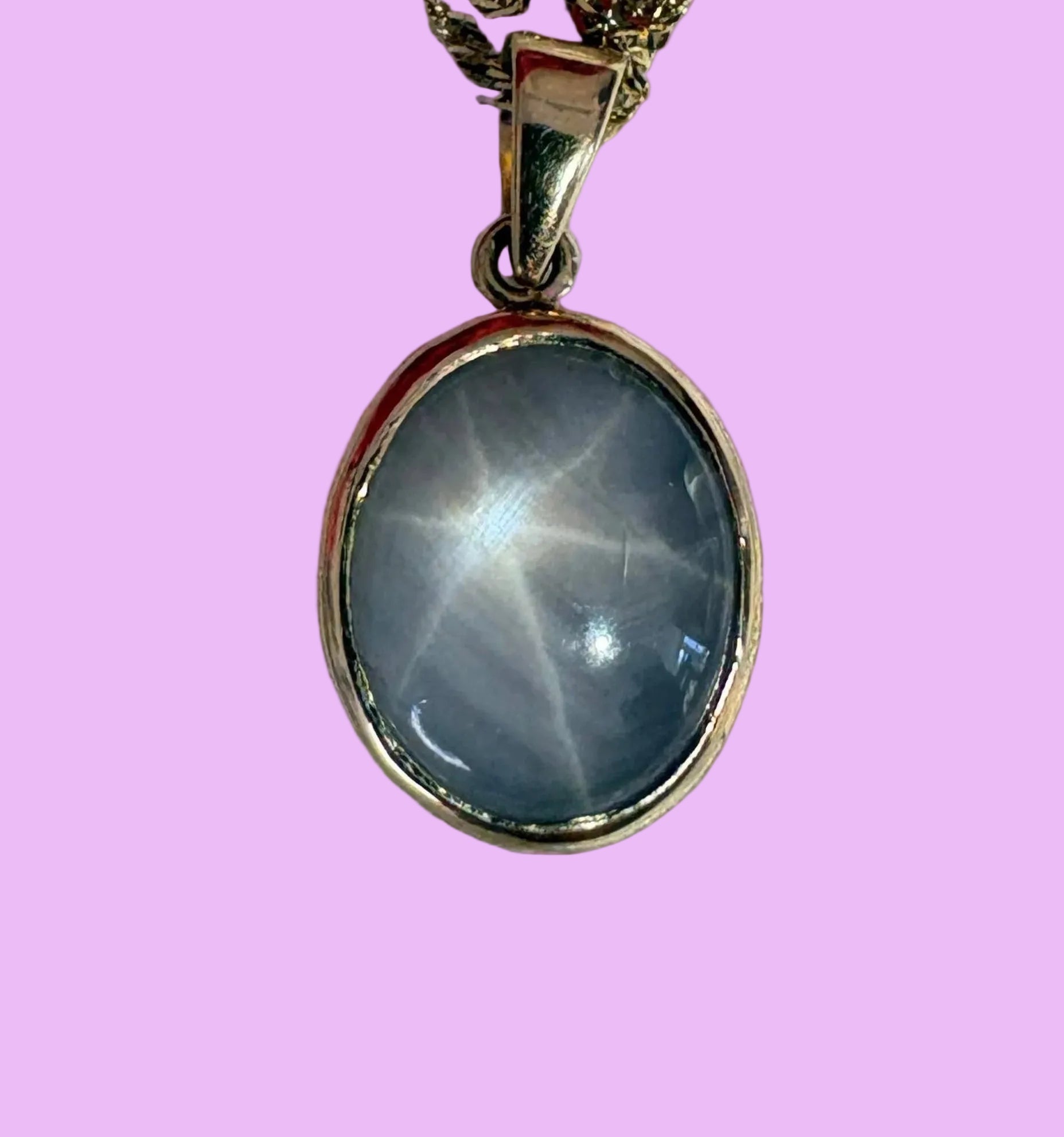 Necklace with a starsapphire pendant on a pink background