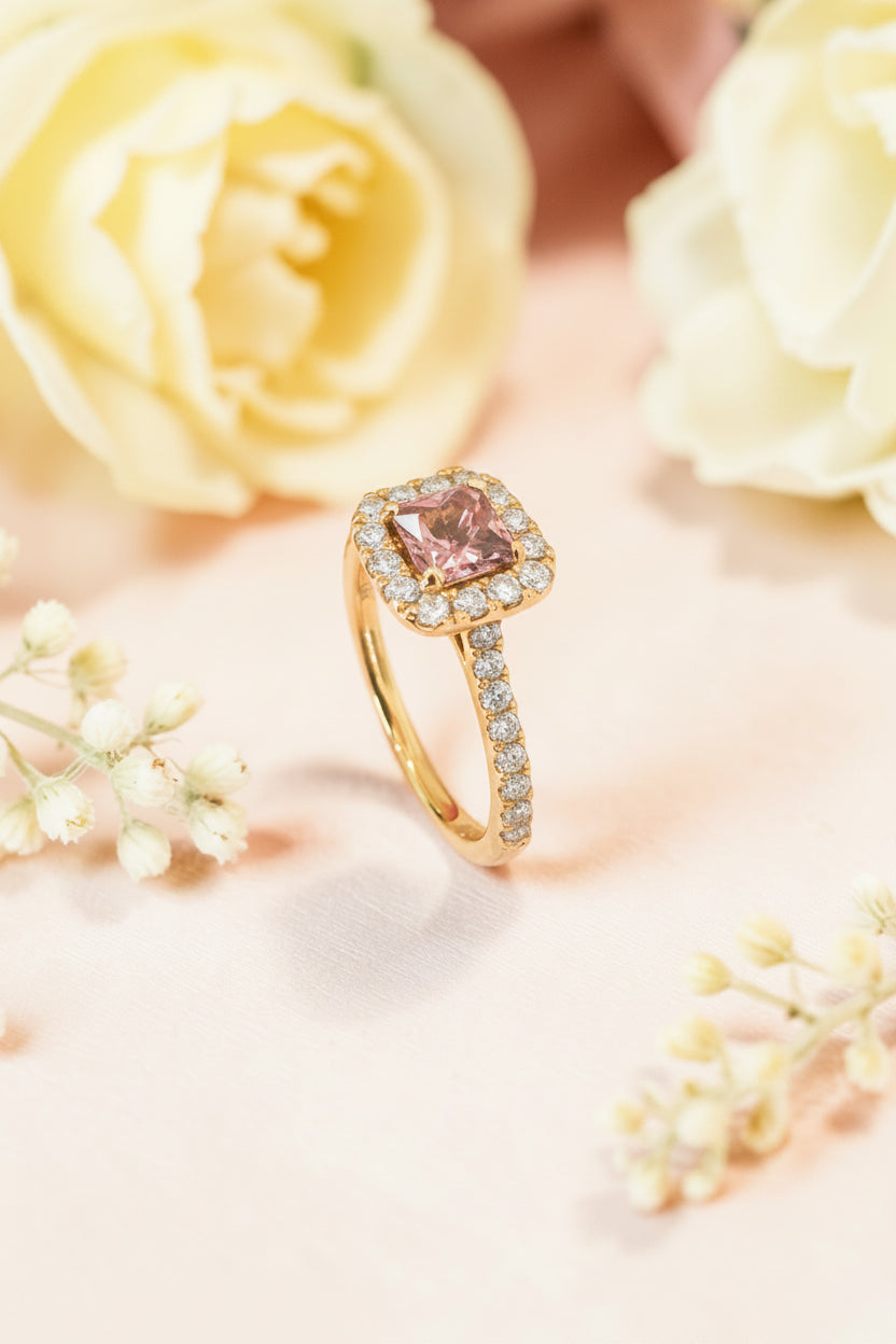 Gold ring with a pink tourmaline and diamonds on a soft pink background with flowers