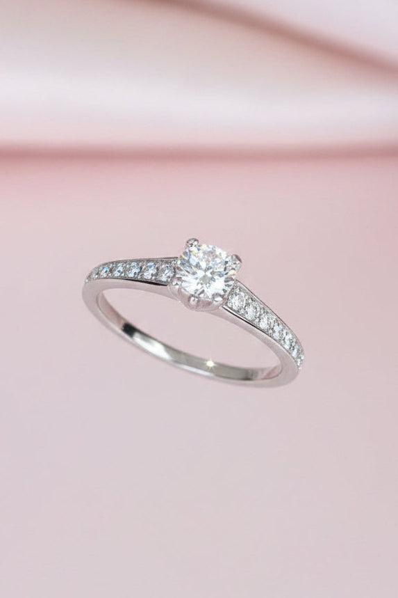 white gold ring with a diamond on a pink fabric background